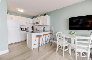 a kitchen with white cabinets and a table and chairs at 1104 Starfish Room by Atlantic Towers in Carolina Beach