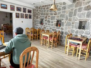 a man sitting in a chair at a table with a laptop at Homestay Pachamama in Cabanaconde