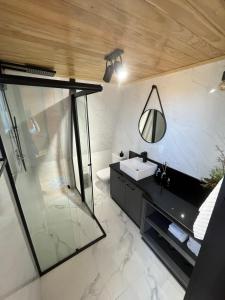 a bathroom with a sink and a glass shower at Chalé Alqualondë -Chácara Valfenda in São Joaquim