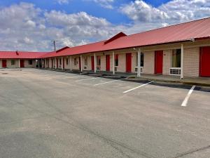 une rangée de bâtiments avec des toits rouges et un parking dans l'établissement Relax Inn Mcgehee, à McGehee
