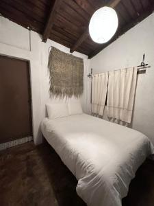 um pequeno quarto com uma cama branca e uma janela em La choza del nahual casa prehispanica tematica em Oaxaca de Juárez