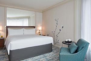 ein Schlafzimmer mit einem Bett und einem blauen Stuhl in der Unterkunft JW Marriott Hotel Hong Kong in Hongkong