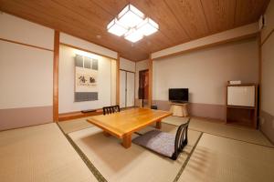 a large room with a wooden table and a tv at Oyado Uraku in Yufu