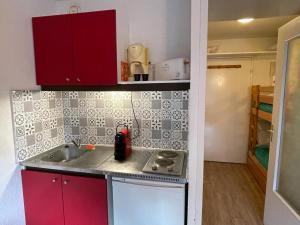 a small kitchen with a sink and red cabinets at Studio Pra-Loup, 1 pièce, 4 personnes - FR-1-165A-177 in Uvernet