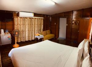 a bedroom with a white bed and a couch at Banthai Guesthouse in Phetchaburi