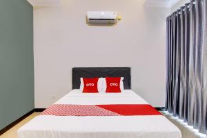 um quarto com uma cama com duas almofadas vermelhas em OYO 92479 Pasadena House em Semarang