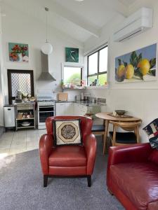 a living room with a red chair and a kitchen at The Partchery Devonport in Auckland