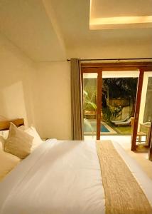 a bedroom with a bed and a large window at Villa Majegau 2 by Deasha in Seminyak