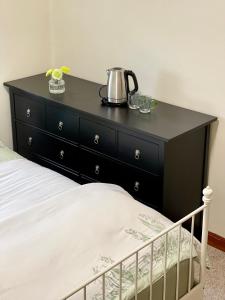 a black dresser with a tea kettle on top of it at Private Bath Ensuite Room Eastwood/MQ Uni park in Sydney