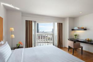 a bedroom with a bed and a desk and a window at Tower Club at lebua in Bangkok