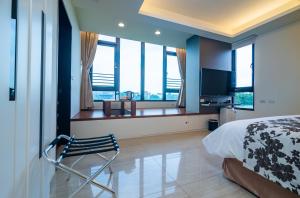 a bedroom with a bed and a chair and windows at Sakura VILLA B&B in Yuanshan