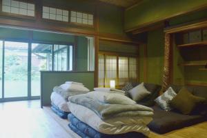 una habitación con una fila de camas y un sofá en 野窓 Nomadノマド Tsuwano GuestHouse & Cafe Lounge en Tsuwano