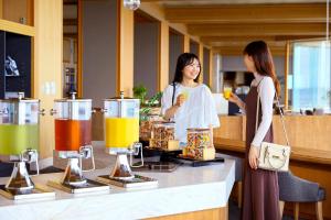deux femmes debout devant un comptoir avec boissons dans l'établissement Ooedo Onsen Monogatari Premium Shiomiso, à Murakami