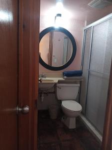 a bathroom with a toilet and a sink and a mirror at Recámara frente al mar, cama King, tv, wifi in Tijuana