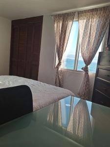 a bedroom with a bed and a glass table with a window at Recámara frente al mar, cama King, tv, wifi in Tijuana