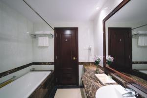 un bagno con vasca e un grande specchio di Saigon Dalat Hotel a Da Lat