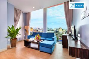 a living room with a blue couch and a large window at HANZ Premium Bamboo Hotel in Ho Chi Minh City