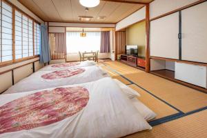 a room with two beds and a flat screen tv at Hotel Shin Makomo in Itako