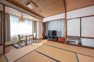 een woonkamer met een tafel en een televisie bij Hotel Shin Makomo in Itako