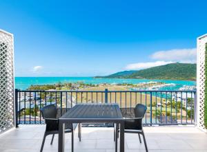 una mesa y sillas en un balcón con vistas al océano en Ocean Views at Whitsunday Terraces Resort en Airlie Beach