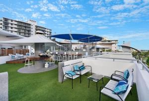 a rooftop patio with chairs and a table and umbrella at Mooloolaba Beach Club Paradise 2 Bedroom Apartment in Mooloolaba