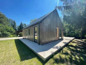 a small wooden cabin with a deck in the grass at Domki Skandynawskie nad Pilicą, Duży Domek 