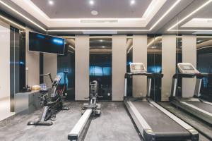 een fitnessruimte met loopbanden en een flatscreen-tv bij Atour Hotel (Wuxi Berkesy) in Wuxi