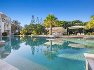 uma piscina com água azul e palmeiras em Drift South Apartments by Kingscliff Accommodation em Casuarina