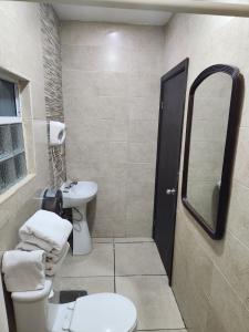 een badkamer met een wastafel, een toilet en een spiegel bij Hotel Don Quijote in Mexicali