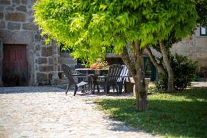 a table and chairs under a tree next to a building at The Big House-grand comfort at Serra da Estrella in Gouveia