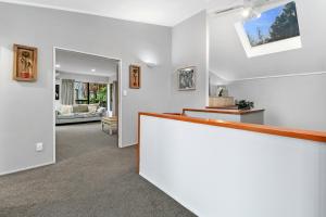 a white room with a counter and a living room at Bushland Retreat - Rotorua Holiday Home in Koutu