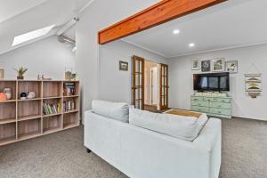a living room with a white couch and a tv at Bushland Retreat - Rotorua Holiday Home in Koutu