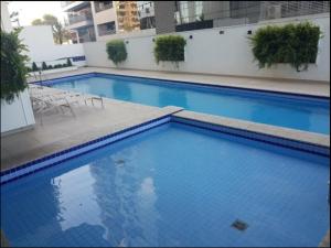 a large blue swimming pool in a building at Conjunto Estudio e Duplex Selenita in Barueri