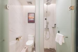 a white bathroom with a shower and a toilet at Atour Hotel (Wuxi Berkesy) in Wuxi