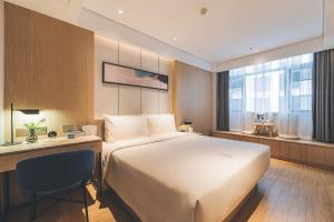 a bedroom with a large white bed and a desk at Atour Hotel (Wuxi Berkesy) in Wuxi