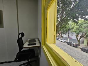 a window with a desk and a chair looking out at a street at Hotel Princesinha do Café in Vassouras