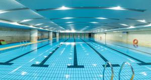 a large swimming pool with blue tile floors and a ceiling at Grand Metropark Hotel Shandong in Jinan