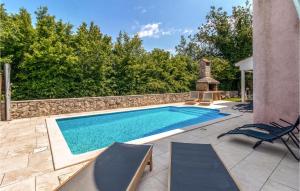 une piscine avec deux chaises et un mur en pierre dans l'établissement Beautiful Home In Dobrinj With Outdoor Swimming Pool, à Dobrinj