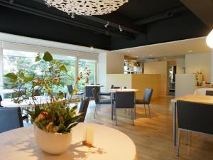 uma sala de jantar com mesas e cadeiras e uma planta em hotel miura kaen em Takikawa