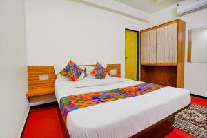a bedroom with a large white bed with colorful pillows at FabExpress Sai Chatra in Nashik