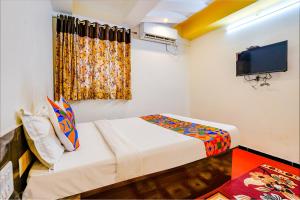 a small room with a bed and a tv at FabExpress Sai Chatra in Nashik