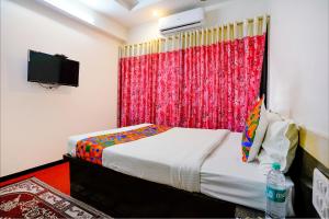 a bedroom with a bed and a red curtain at FabHotel Sai Chatra in Nashik