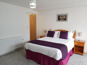 a bedroom with a large bed with purple and white sheets at Runnacleave Court, apartment 2 in Ilfracombe