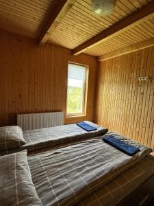 two beds in a wooden room with a window at Котеджі Зоряне Небо in Bukovel