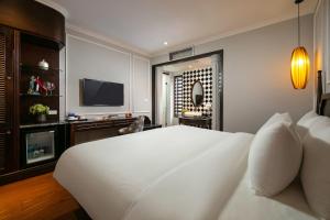 een slaapkamer met een groot wit bed en een televisie bij Salute Premium Hotel & Spa in Hanoi