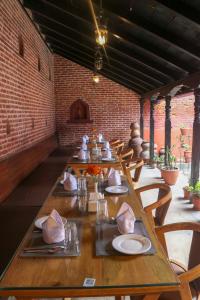a long table in a room with chairs and a brick wall at Hotel Garuda in Bhaktapur