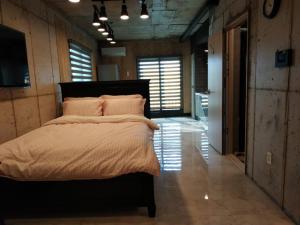 ein Schlafzimmer mit einem großen Bett in einem Zimmer mit Fenstern in der Unterkunft Soo Stay in Seogwipo