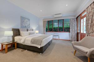 a bedroom with a bed and a chair and windows at Wrenfield Cottages in Marysville