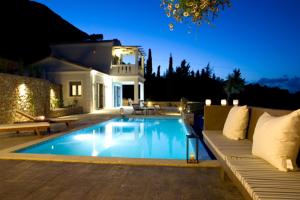 a swimming pool in front of a house at night at Elixrison Villas - Sea view Villa near Nidri in Nikiana