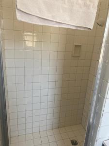 a white tiled shower with a white towel on top at Johnston's Motel in Garberville